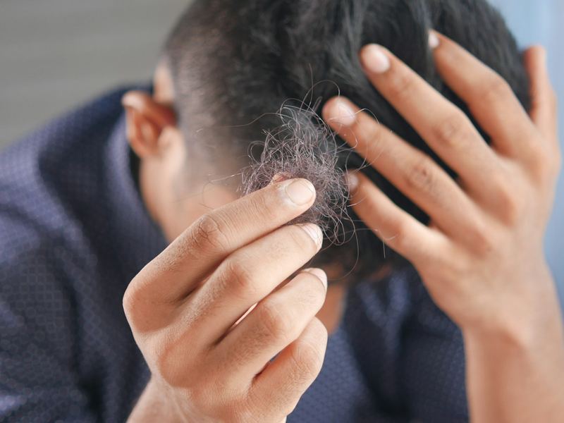 Close-up of hands running through hair at the scalp