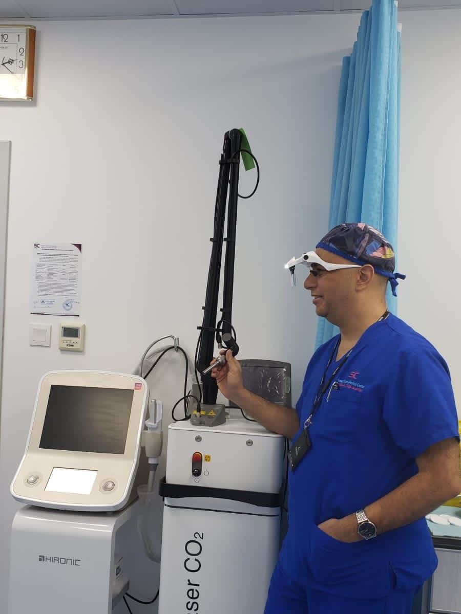 Dr. Mohamed Hussein holding the handpiece of a fractional CO2 laser in the treatment room at Smart Care Medical Center